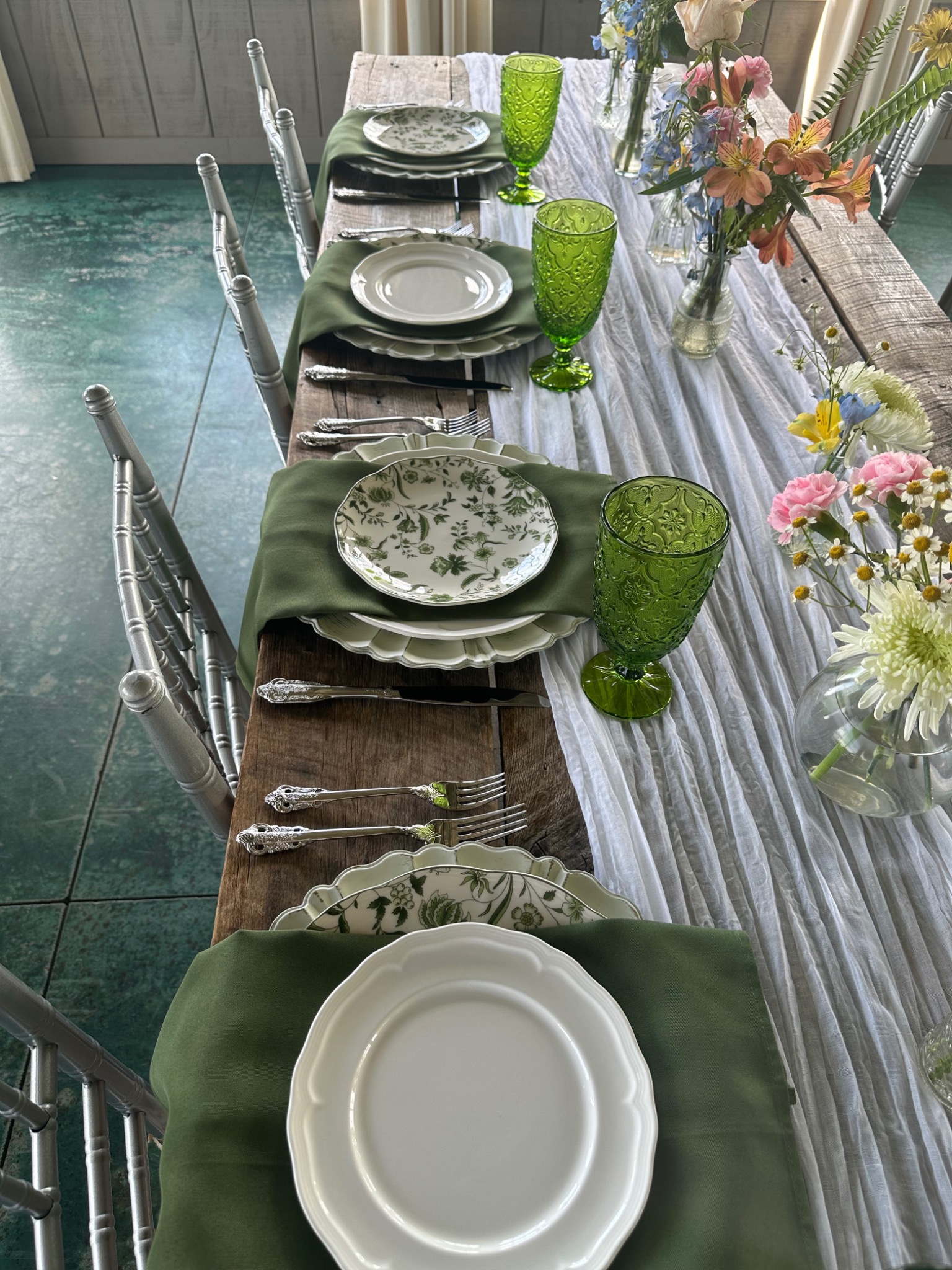 Green and white wedding table setting with colorful flowers